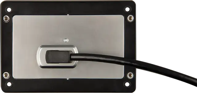 Metallic panel with a black cable plugged into it on a white background